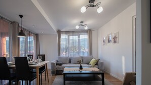 Ein modernes Wohnzimmer mit Essbereich, ausgestattet mit einer Couch, einem Couchtisch und einem Esstisch mit Stühlen.