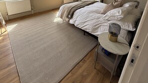 Ein Schlafzimmer mit einem Bett, einem Nachttisch, einem Heizkörper, einem Fenster und einem Kleiderschrank.