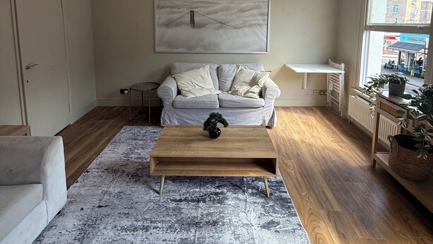 Ein stilvolles Wohnzimmer mit einer Couch, einem Couchtisch und einem Bild an der Wand.