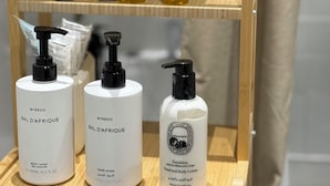 Ein Holzregal mit verschiedenen Pflegeprodukten, darunter Körperlotion, Shampoos und Duschgel.