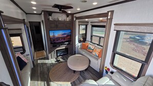 A compact living space with a television, seating area, and large windows offering views of the outdoors. - Luxury Glamping Oasis: Superstition Mtns, Views & Nearby Lakes (Apache Junction)