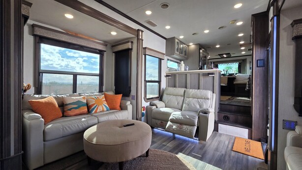 A modern RV interior with a sofa, ottoman, and a cushioned chair. - Luxury Glamping Oasis: Superstition Mtns, Views & Nearby Lakes (Apache Junction)