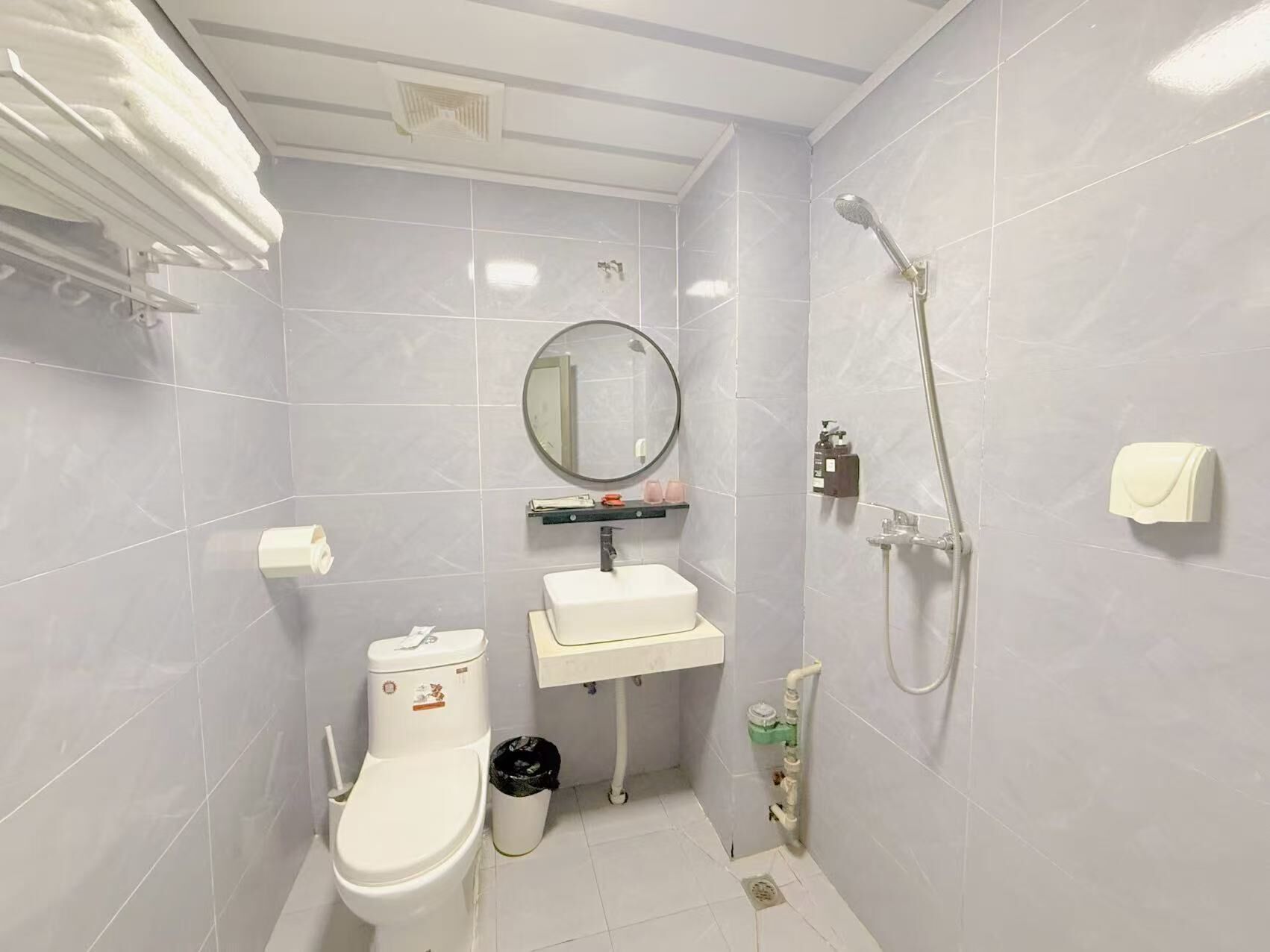 A compact bathroom with a toilet, sink, and shower.