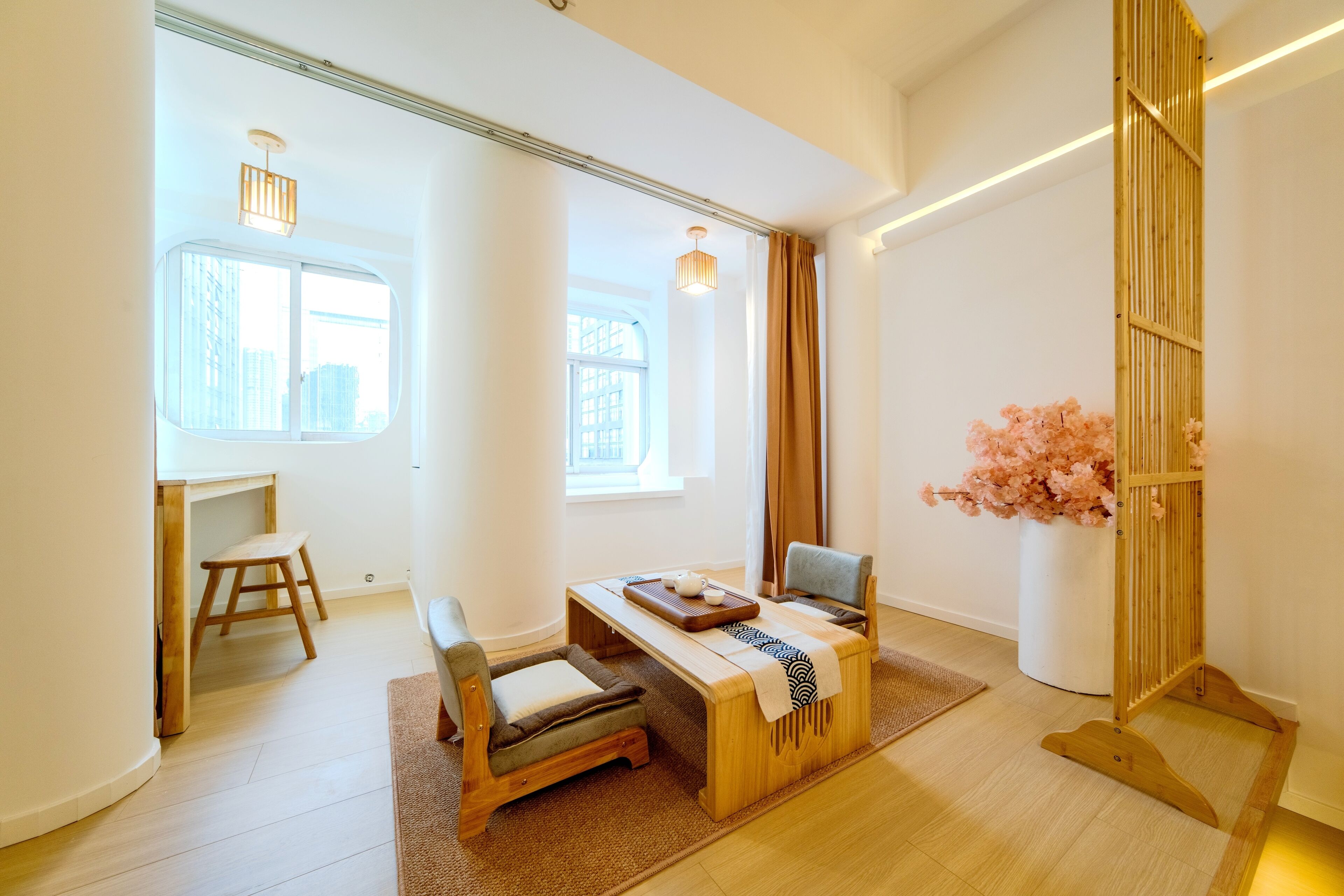 A minimalist room with a wooden desk, a cushioned bench, and a small table with a tray.