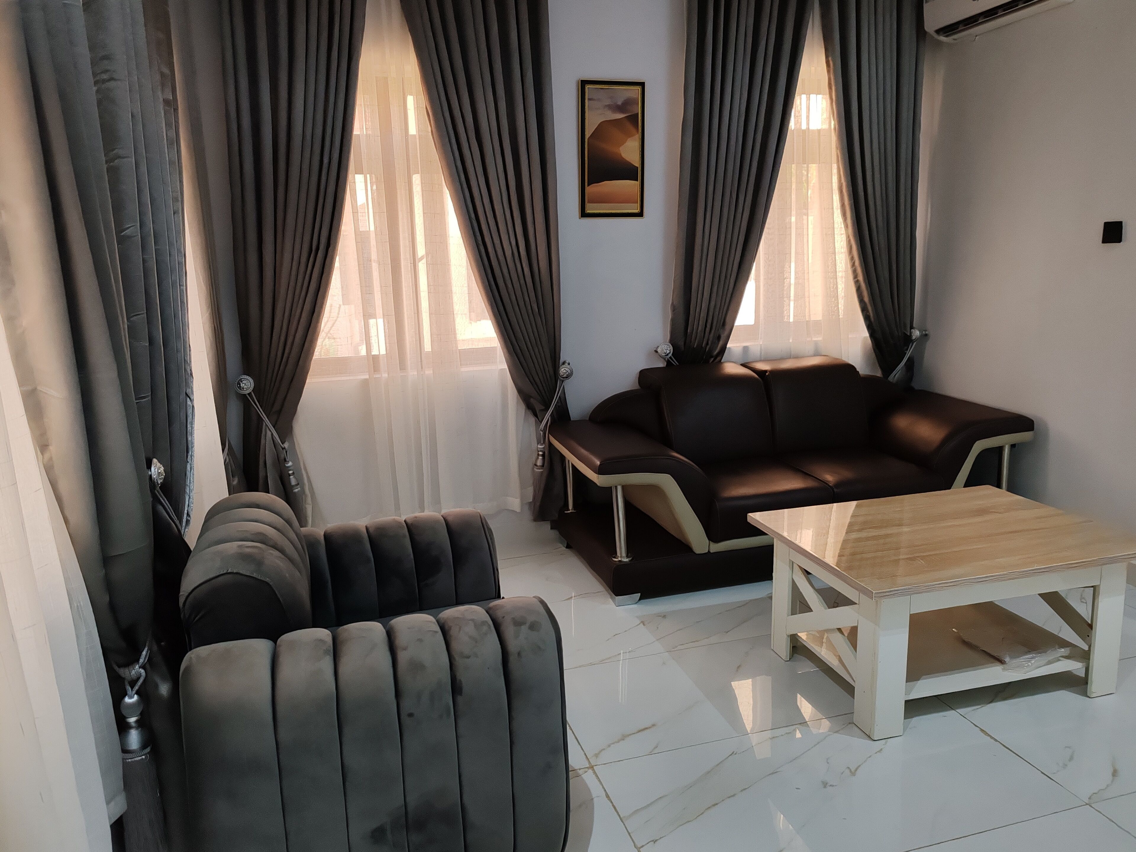 A modern living room with a leather sofa, a wooden coffee table, and a pair of armchairs.