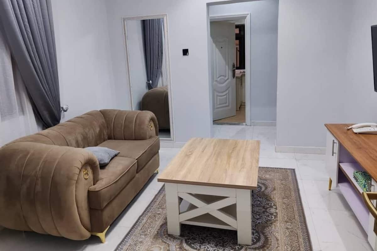 Un salon avec un canapé beige, une table basse en bois et un tapis à motifs.