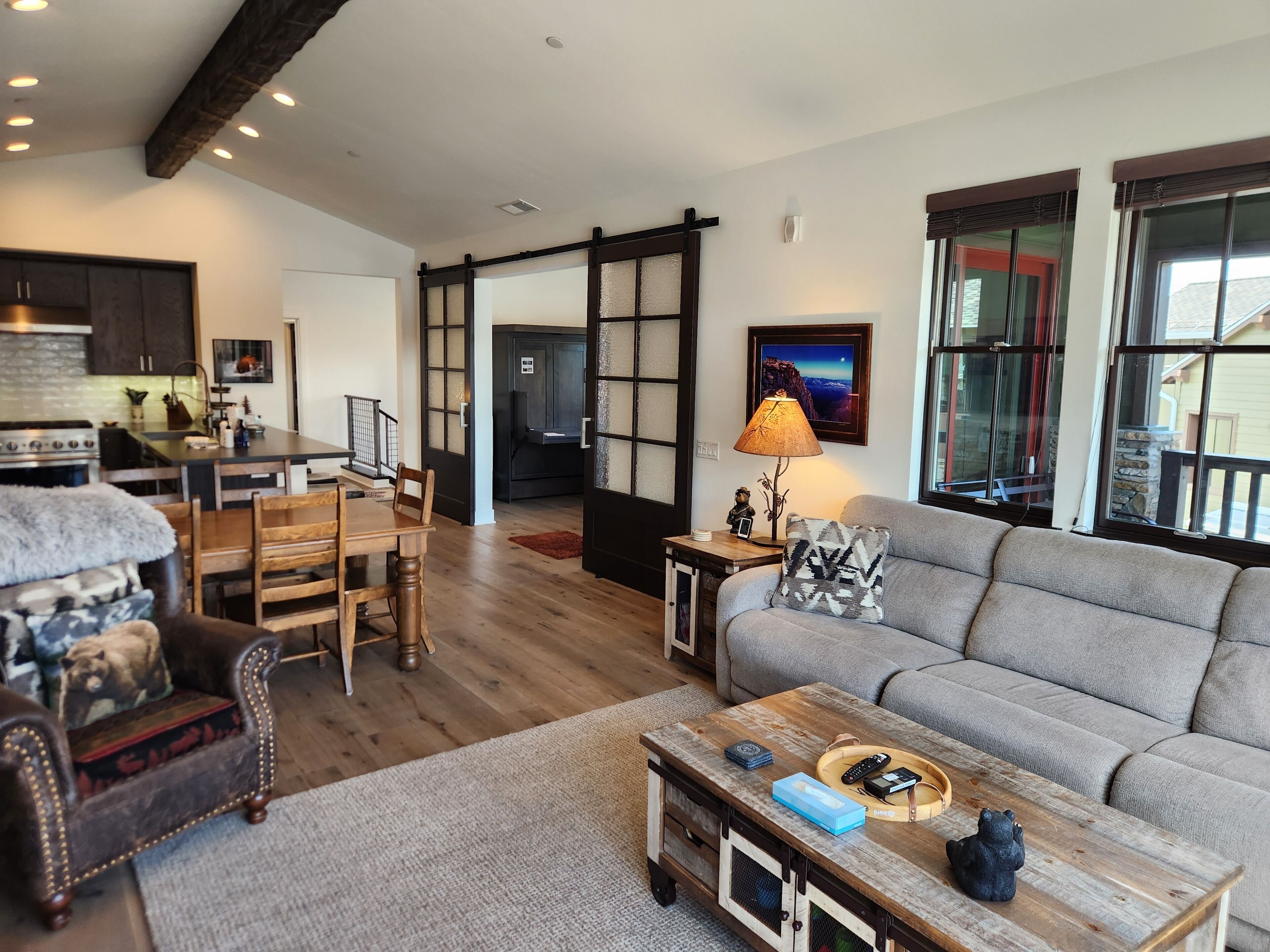 A modern living room with a sofa, a coffee table, and a dining area with a wooden table and chairs.