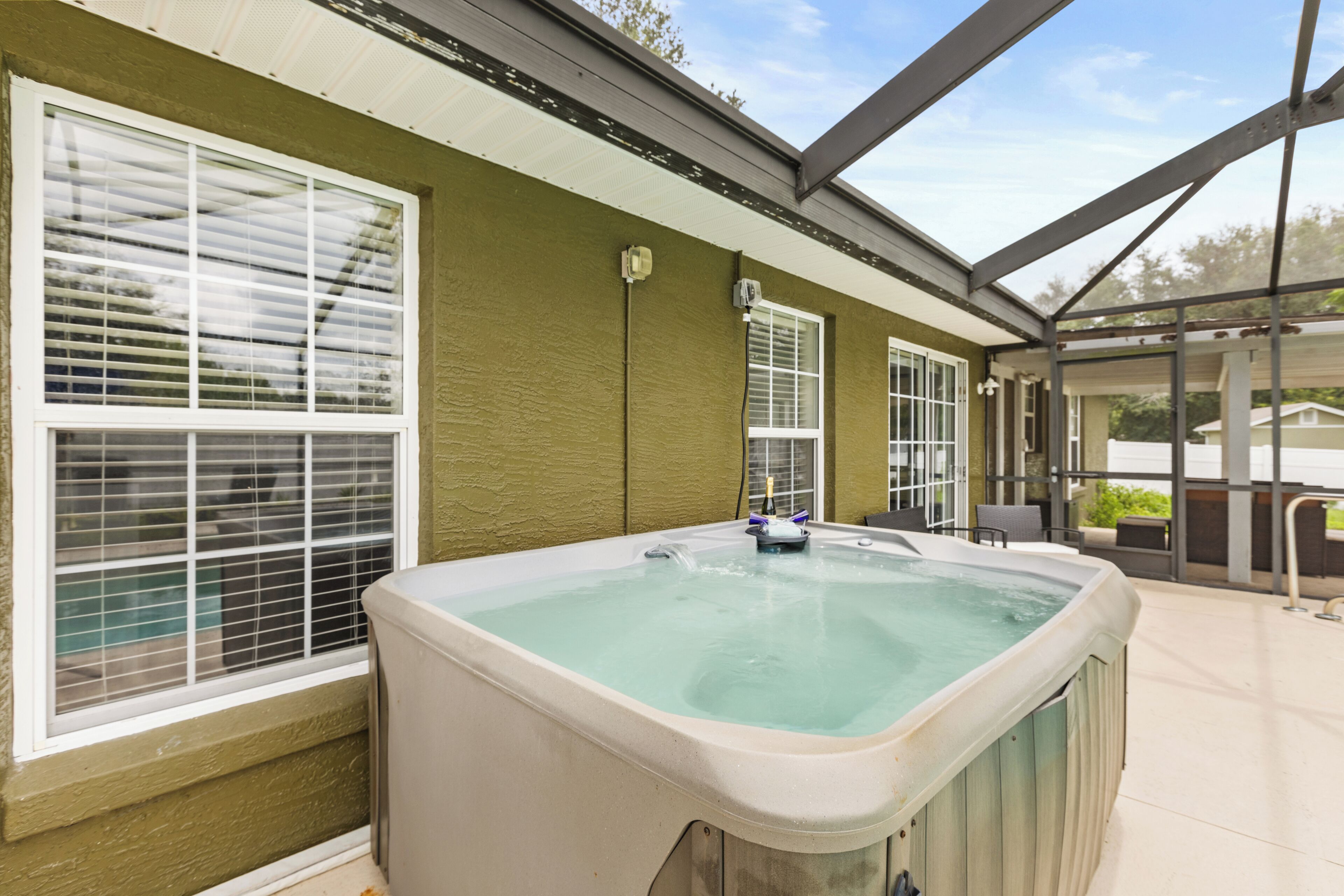 A hot tub in a covered outdoor area with large windows and a view of the surrounding landscape.