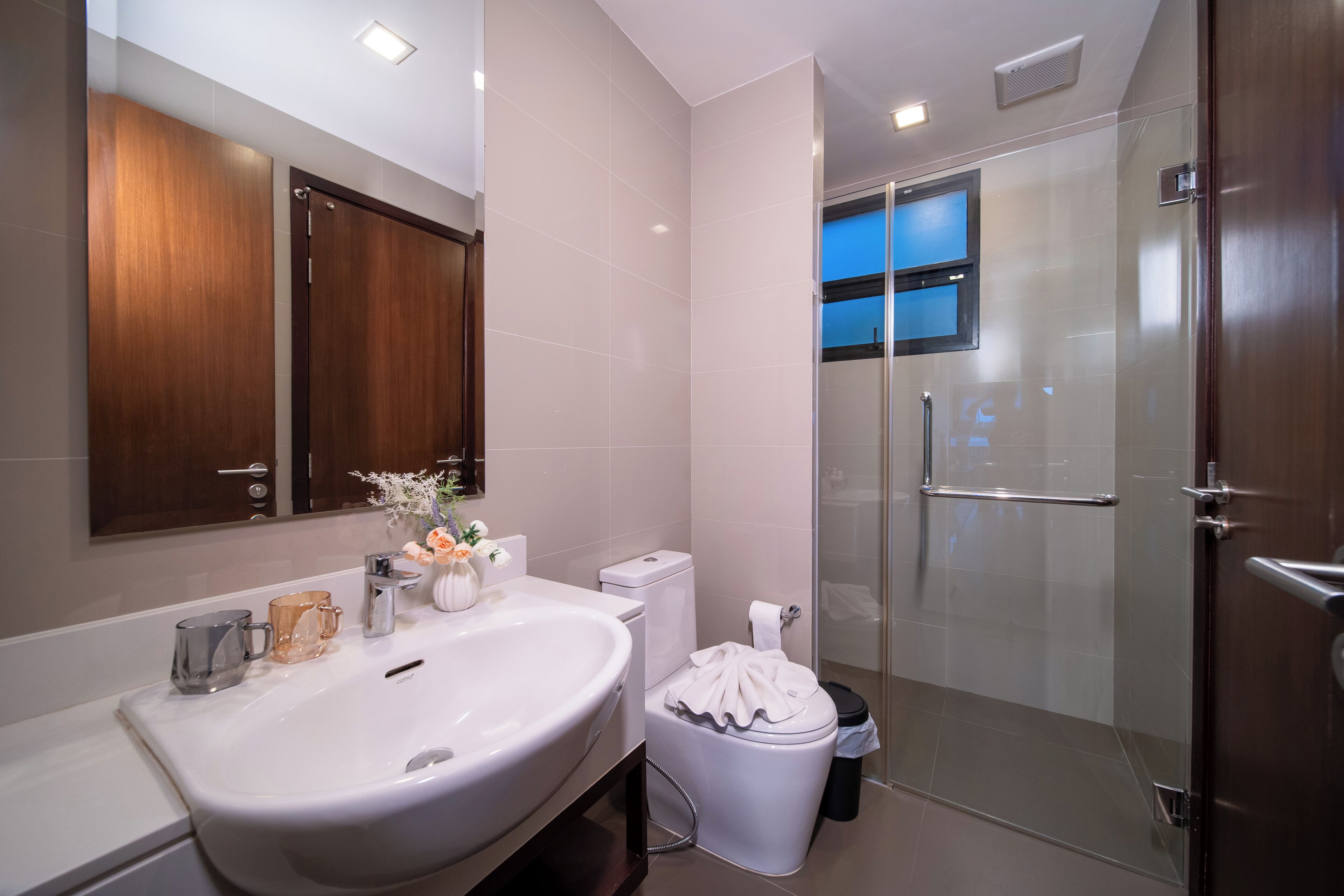 A modern bathroom with a large sink, toilet, and glass-enclosed shower.