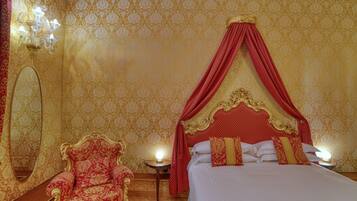 A luxurious bedroom with a canopy bed, ornate chair, and a mirror.