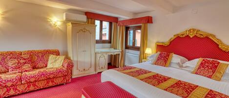 A hotel room with a large bed, a sofa, a desk, and a wardrobe.