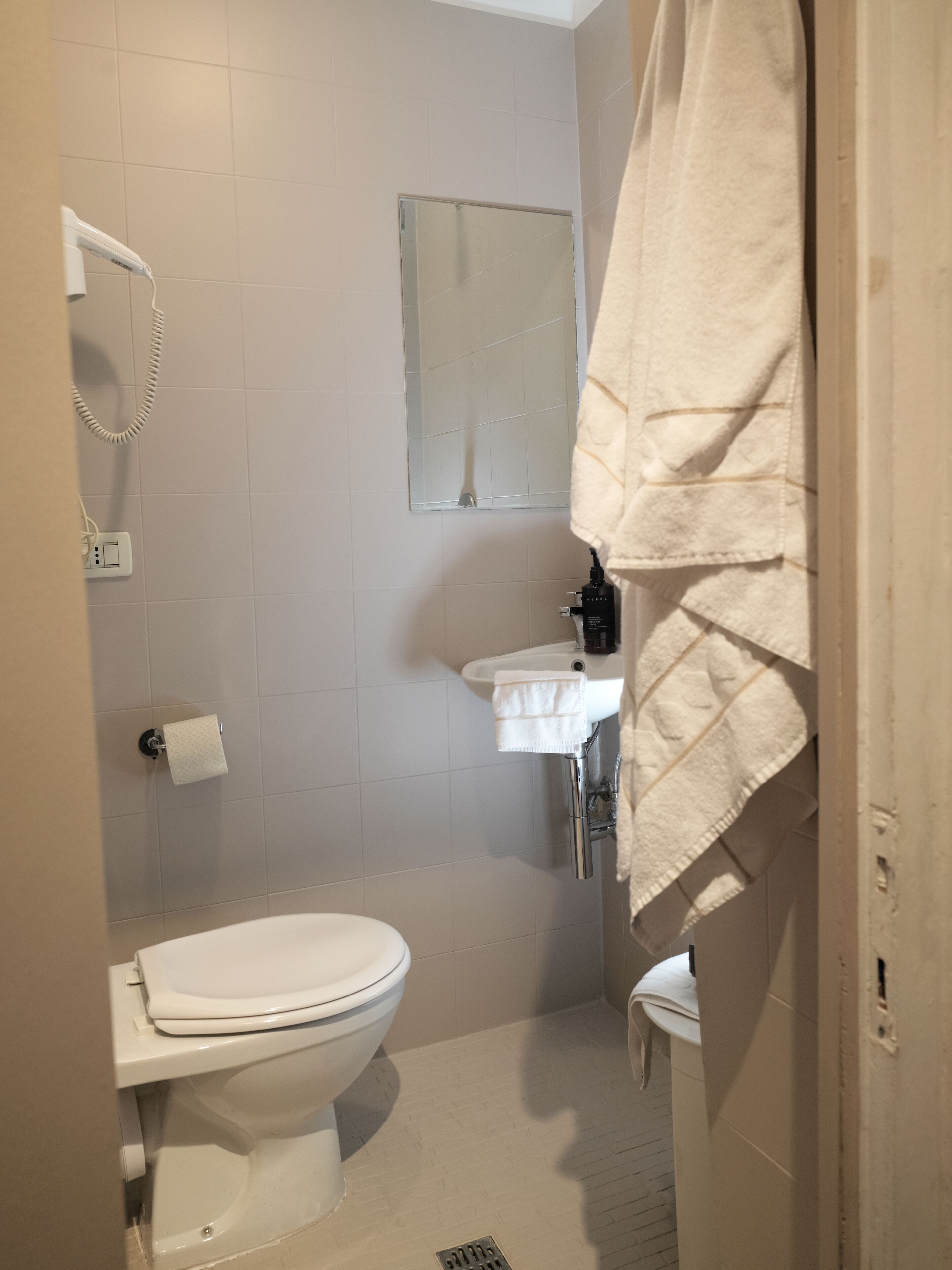 Une salle de bain équipée de toilettes, d’un lavabo et d’un porte-serviettes.