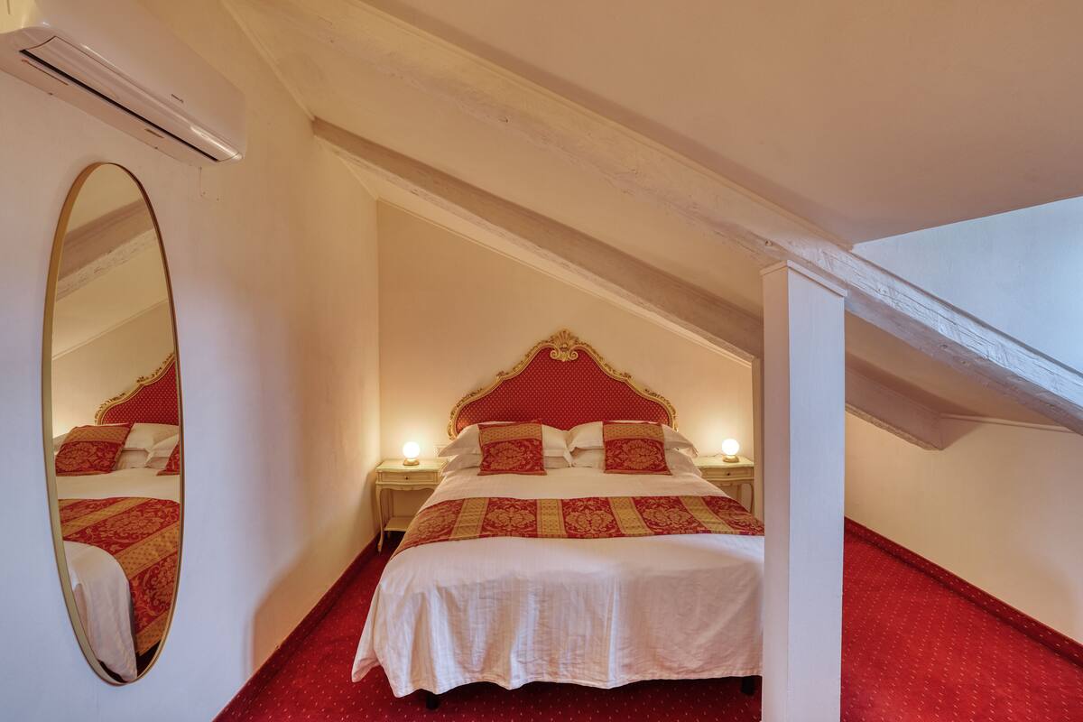 A bedroom with a bed, a mirror, and a nightstand.