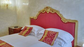 A hotel room with a large bed, a wooden nightstand, and a wall-mounted light fixture.