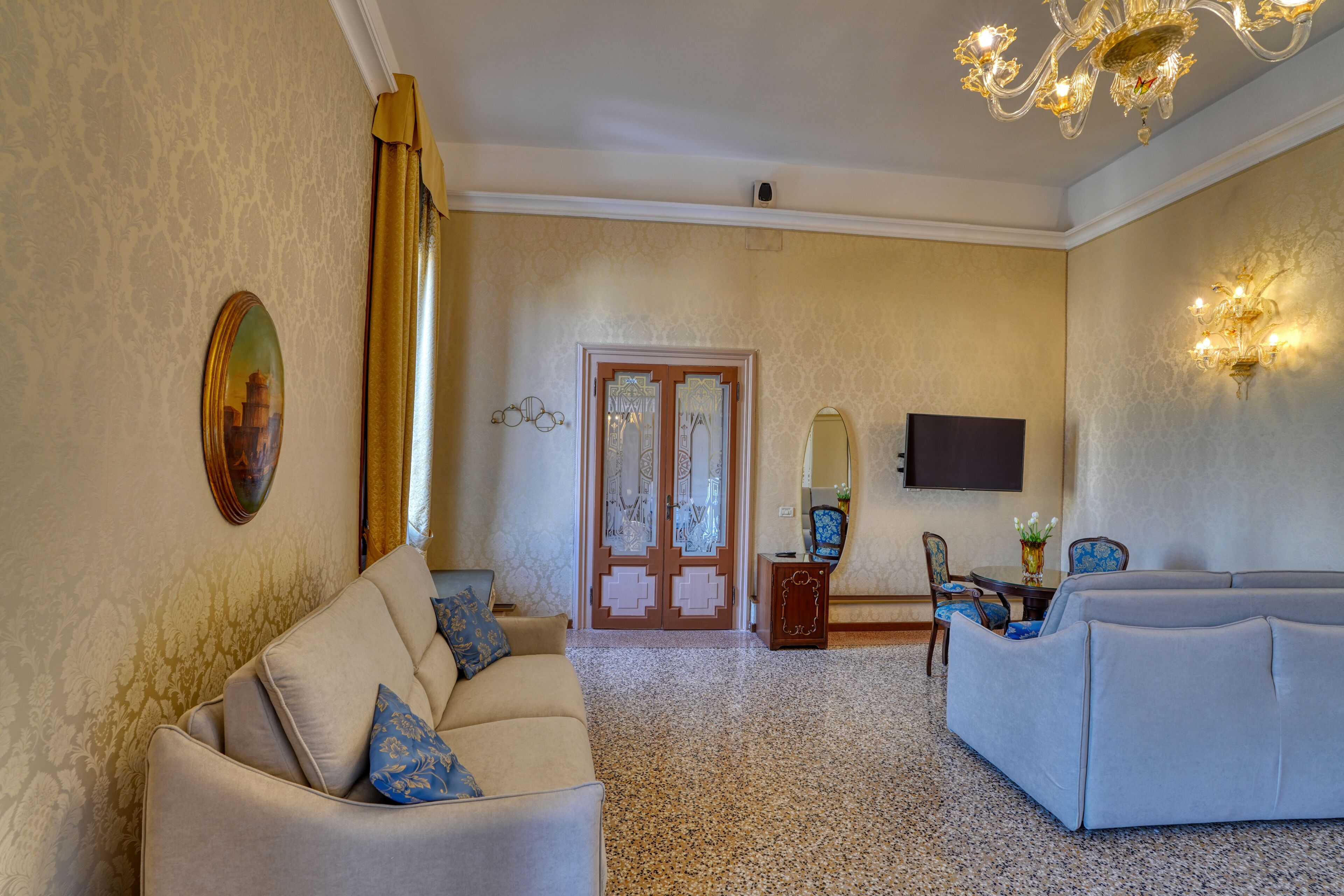 A living room with a sofa, a loveseat, a television, and a door with a mirror.