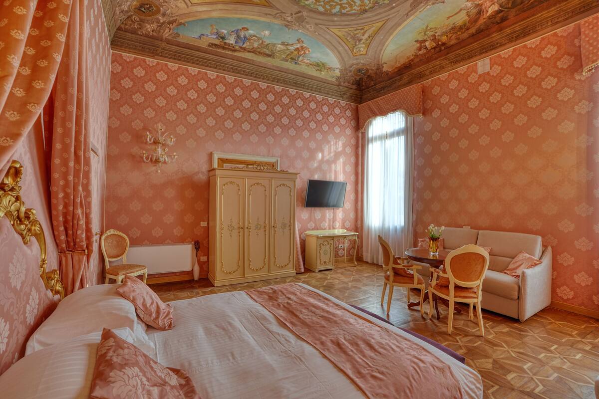A room with a bed, a television, a sofa, a desk, and a chair.
