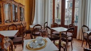 A dining area with wooden furniture, a marble table, and a view of buildings through large windows. - PALAZZO MALIPIERO TREVISAN - LE TRE DIMORE D'EPOCA (Venice)