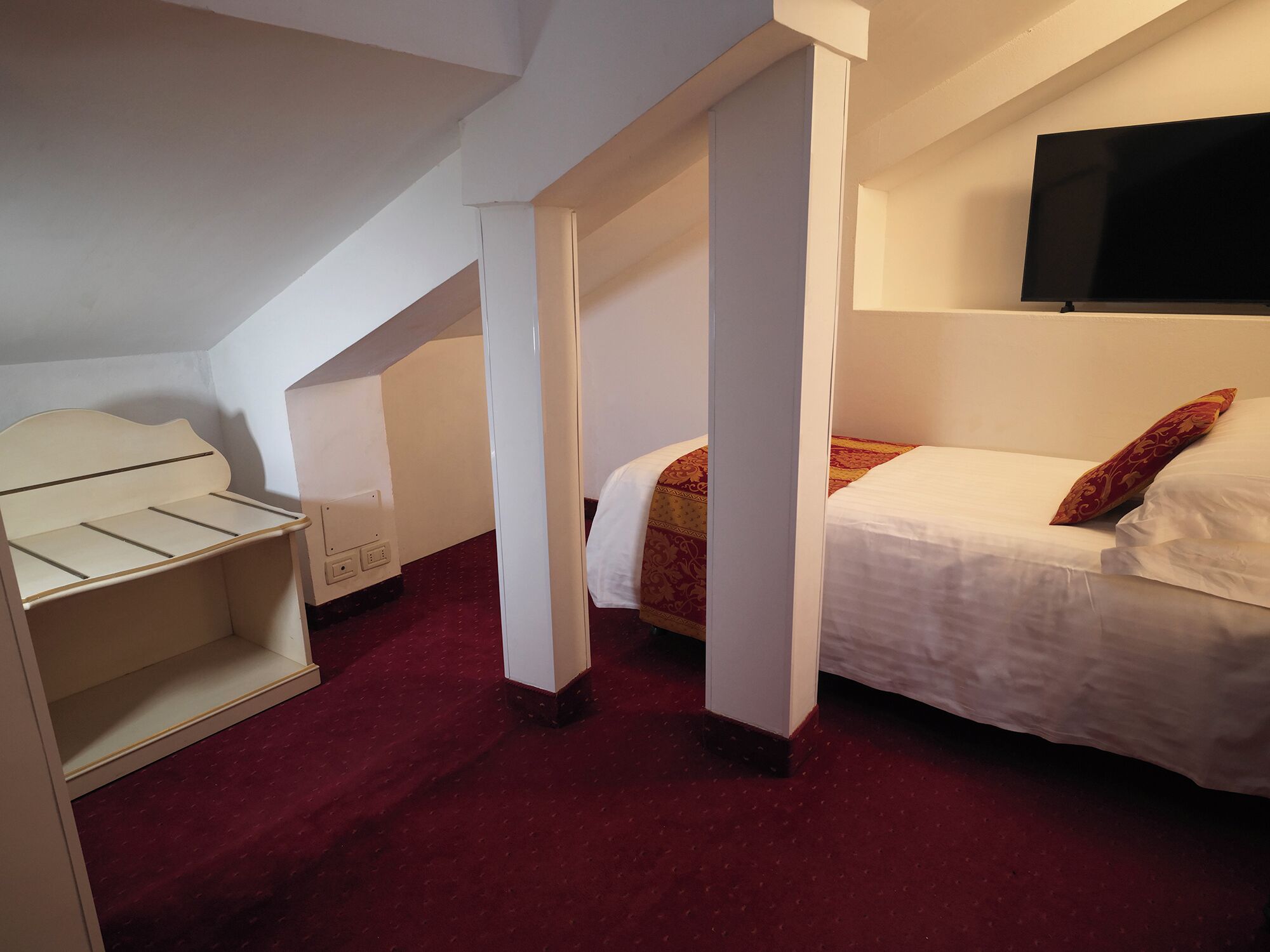 Ein Schlafzimmer mit einem Bett, einem Fernseher und einem Schreibtisch mit Schubladen.
