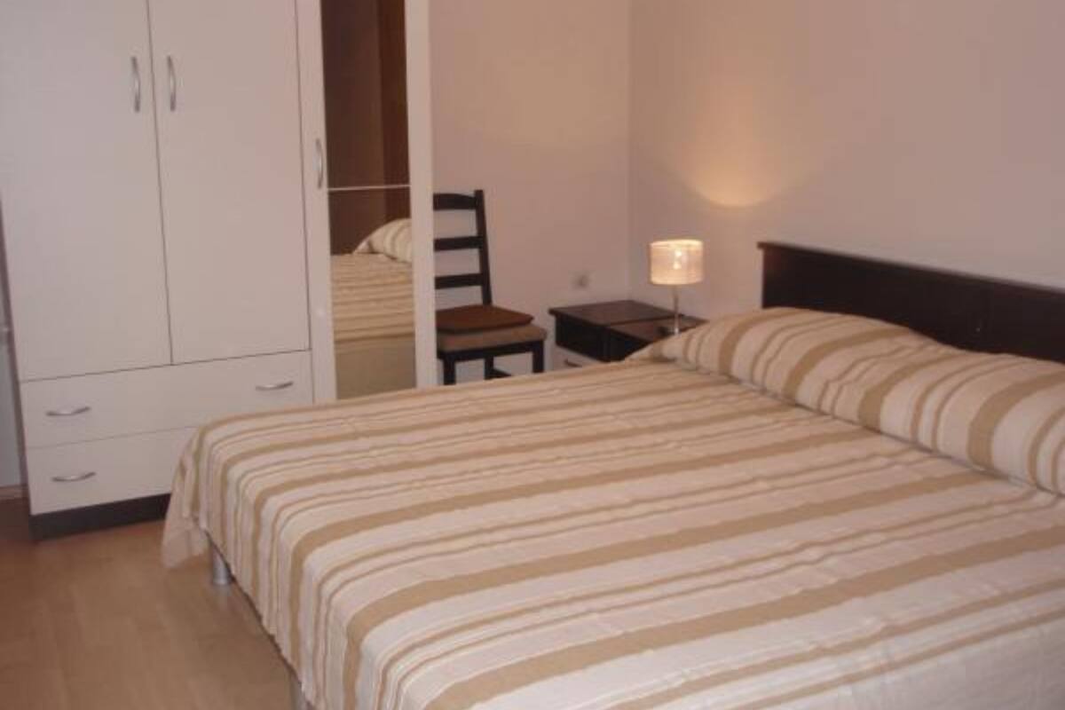 A bedroom with a bed, a chair, a nightstand, and a wardrobe.
