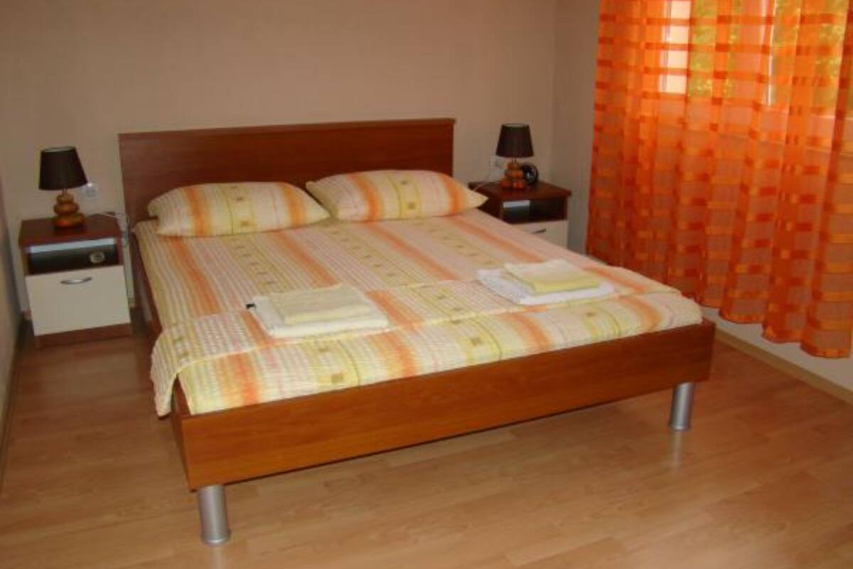 A neatly made bed with a striped bedspread, two bedside tables with lamps, and a wooden floor.