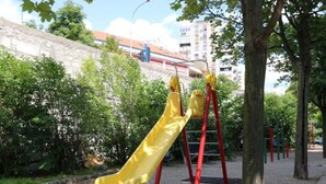 A playground with a yellow slide and red climbing structure, surrounded by trees and a building in the background. - City Apartments Iva Krimeja Rijeka (Rijeka)