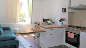 A compact kitchen with a dining area, a sofa, and a window with curtains. - City Apartments Iva Krimeja Rijeka (Rijeka)