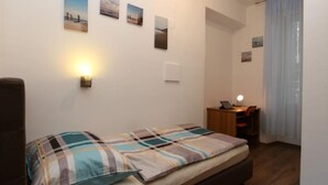 A bedroom with a bed, a desk, and a chair. There are four wall-mounted pictures. - City Apartments Iva Krimeja Rijeka (Rijeka)