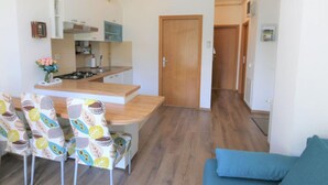A compact kitchen with a dining area, a blue sofa, and a wooden door. - City Apartments Iva Krimeja Rijeka (Rijeka)