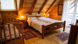 Une pièce chaleureuse en bois, avec un lit, des tables de chevet, un berceau et un bureau.