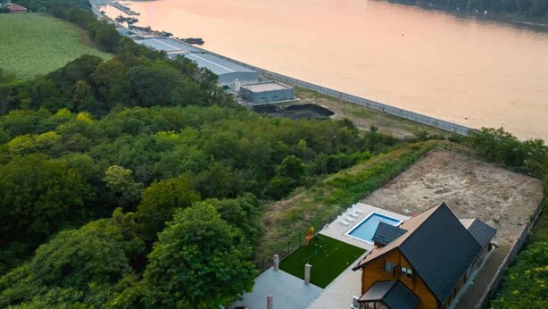 Une propriété située au bord de la rivière, comprenant une piscine, une petite maison et un pont.