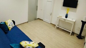 Una habitación con cama, escritorio, televisor y armario.