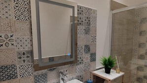 Un baño con lavamanos blanco, un espejo y azulejos con diseño.