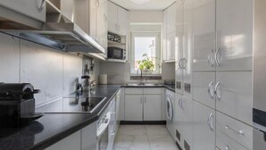 A modern kitchen with stainless steel appliances, white cabinetry, and a black countertop. - Zagreb Downtown Luxury Stay – 5th Element (Zagreb)