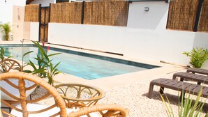 A pool area with wicker chairs, a glass table, and a small garden with pebbles and plants. - Villa 3 suites, private pools, comfort & relaxation (Provincia de guanacaste)