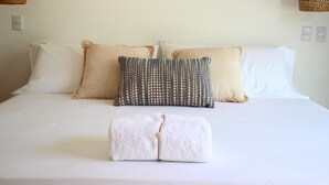 A neatly made bed with white linens, two beige pillows, and a patterned pillow. - Villa 3 suites, private pools, comfort & relaxation (Provincia de guanacaste)