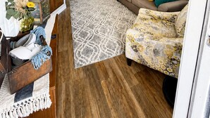 Un salon comprenant un canapé, un fauteuil et un coin repas avec des chaises.