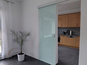 A modern kitchen with wooden cabinets, a black countertop, and a coffee maker. - Niemann 4 Vacation Apartment with Private Garden/Terrace   (Lübeck)