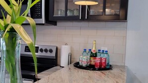 A kitchen with a marble countertop, a hanging light fixture, and a plant in a glass vase. - Secluded Contemporary 2BR 2BA Suite (Dundas Town)