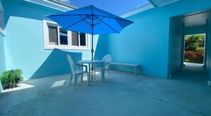 A blue-painted exterior wall, a white door, and a concrete patio with a table and chairs.