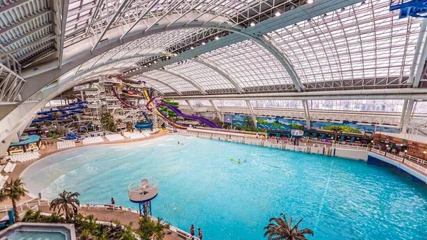An indoor water park with a large pool, slides, and a covered area with seating. - Luxe Escape Duo - 8 Beds - Sleeps 22 - 4 Car Garage (Edmonton)
