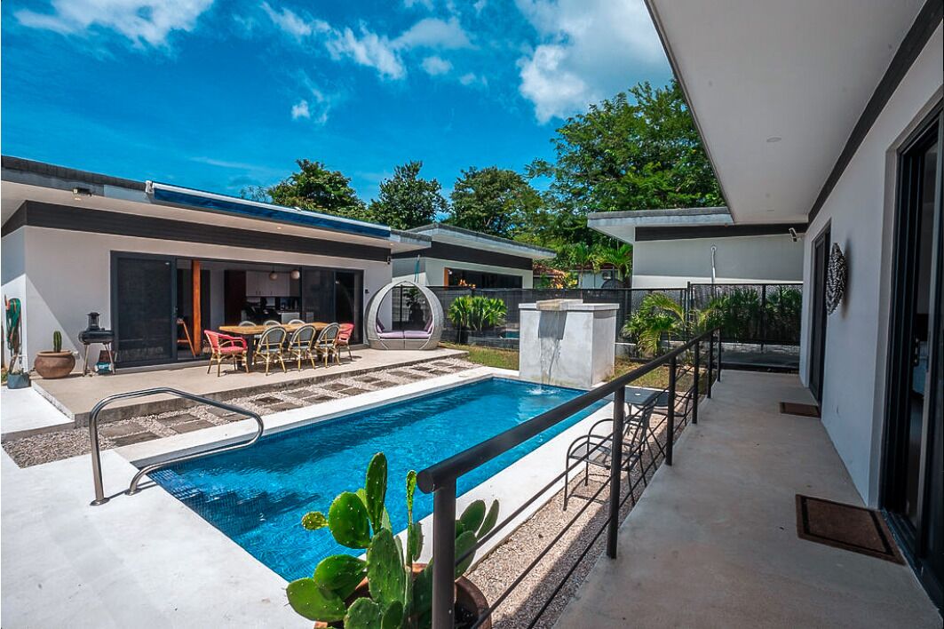 Ein modernes Haus mit Schwimmbad, Sitzgelegenheiten im Freien und einer Terrassenfläche.