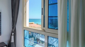 Una habitación con un ventanal amplio que ofrece vistas al mar y a edificios.