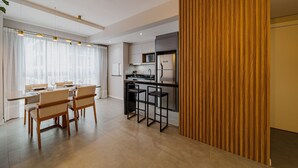 A modern kitchen with a bar area, wooden paneling, and a dining area with chairs and a table. - Morse Residencial Flipchave MOR000 (Joinville)