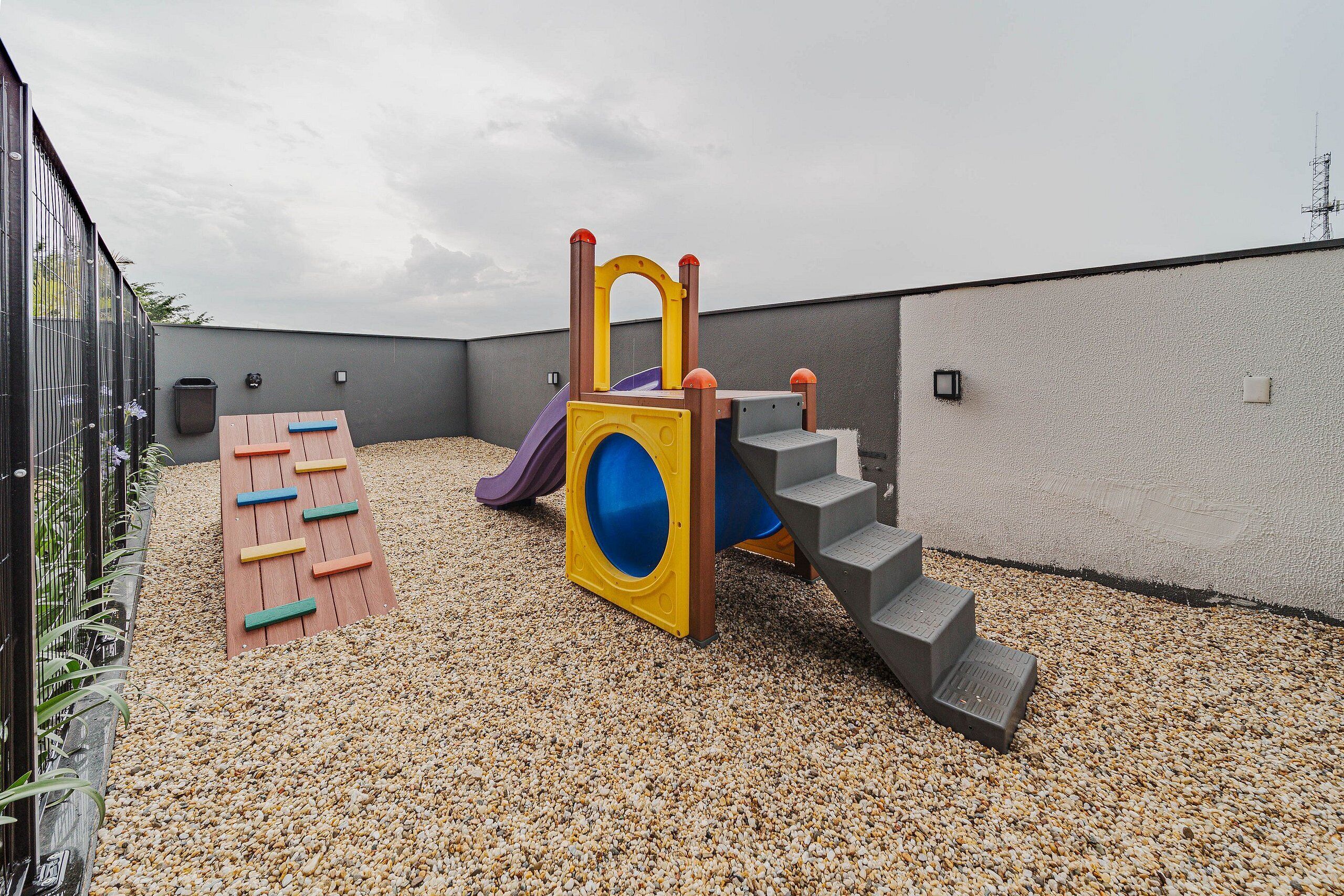 Un parque infantil con tobogán, escaleras de acceso y una piscina de pelotas.