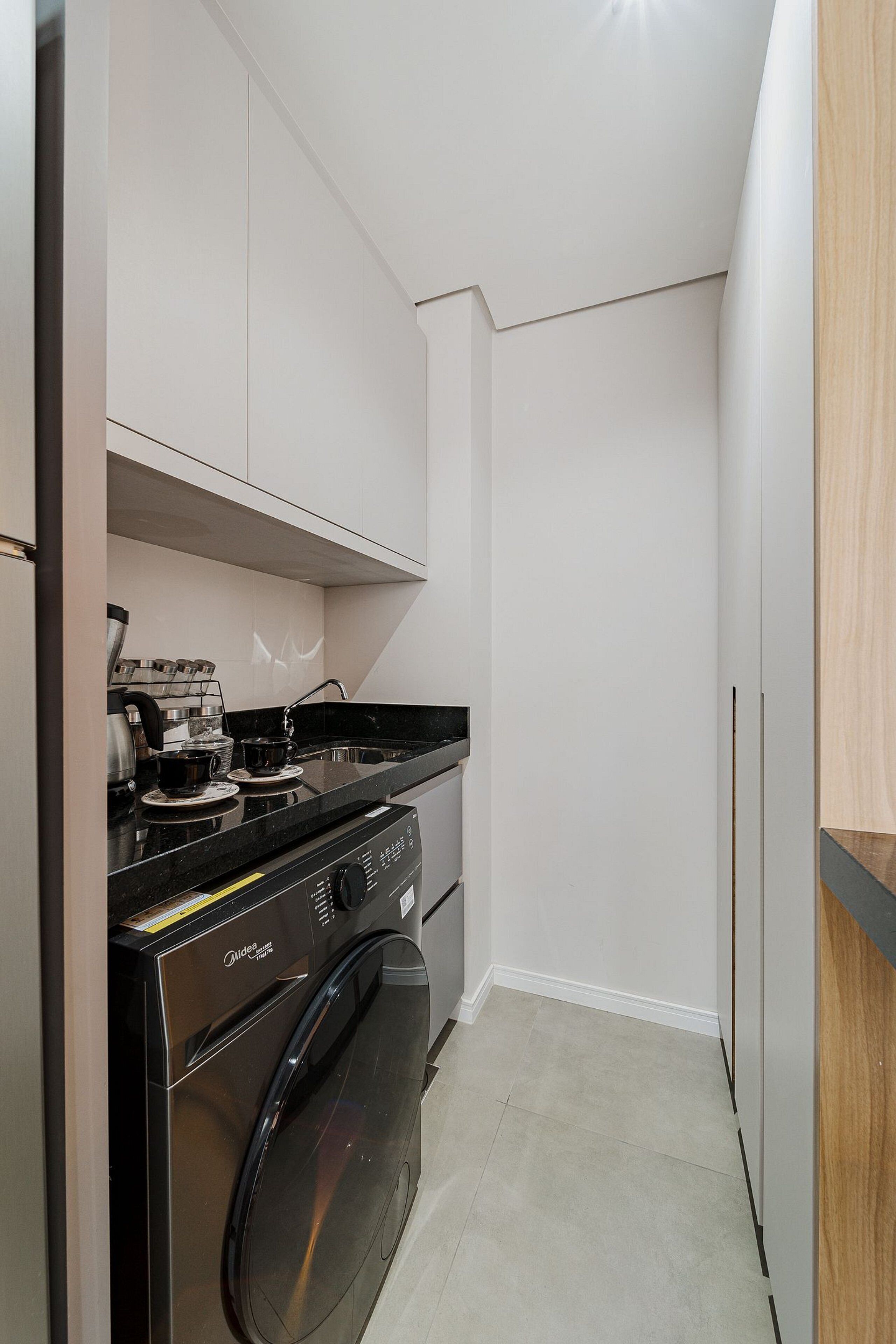 A compact kitchen with a washing machine, a stove, and a sink.