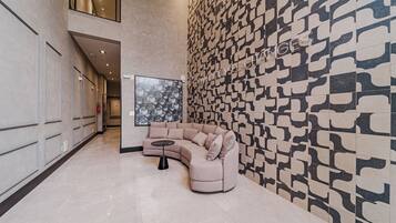 Eine moderne Lobby mit einer gebogenen Couch, einem kleinen runden Tisch und einer Wand mit Muster.