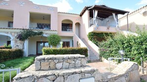 Un edificio de varios pisos con balcones, escalones de piedra y un jardín.
