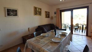 Un comedor con una mesa dispuesta para dos, un sofá y vistas al exterior.