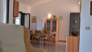 Un soggiorno con divano, tavolo da pranzo con sedie, frigorifero e mobile.
