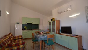Un ambiente compatto con angolo ristoro, angolo cottura e televisione.